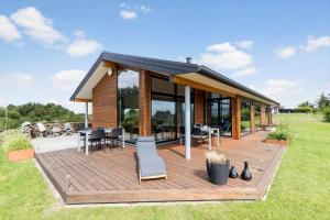 a house with a deck with chairs and tables at 84213-Ebeltoft-Lokevej-8 in Ebeltoft