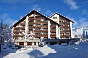 un grand bâtiment avec de la neige devant lui dans l'établissement Hotel Laaxerhof, à Laax