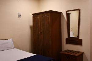 a bedroom with a wooden cabinet and a mirror at Vybhav Residency AC in Anantapur