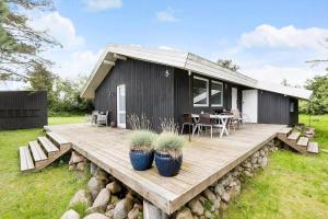 a black house with a wooden deck with plants at 8211-Knebel-Basbjergvej-5 in Knebel +17 photos