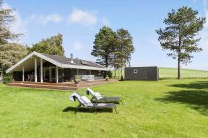 a house with two lounge chairs in a field at 8211-Knebel-Basbjergvej-5 in Knebel