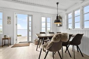 a dining room with a table and chairs with a view of the ocean at 8113-Ronde-Strandvejen-91 in Rønde +18 photos