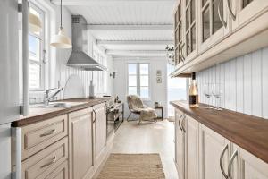 a kitchen with white cabinets and a sink and a chair at 8113-Ronde-Strandvejen-91 in Rønde