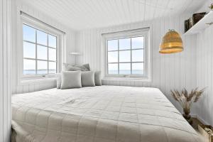 a white bedroom with a large bed with two windows at 8113-Ronde-Strandvejen-91 in Rønde