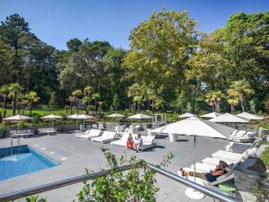 a pool with lounge chairs and umbrellas next to a pool at Novotel Resort & Spa Biarritz Anglet in Anglet