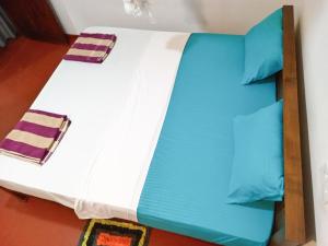 a bed with blue and white sheets and pillows at Vintage rooms in Dickwella