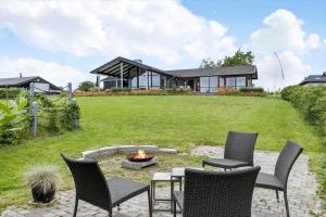 a backyard with chairs and a fire pit and a house at 84164-Ronde-Stenhojvej-17 in Rønde