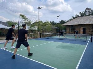 a group of people playing tennis on a tennis court at Tadom Hill Resorts in Kampong Labohan Dagang