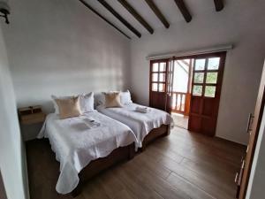 a bedroom with two beds with white sheets at Hotel Boutique Villa Amonita in Villa de Leyva