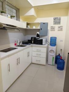 a kitchen with white cabinets and a sink and a refrigerator at Pico hamilo coast condotel suite in Nasugbu