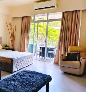 a bedroom with a bed and a chair and a balcony at Pico hamilo coast condotel suite in Nasugbu