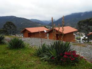 a house on a hill with flowers in front of it at Pousada Bela Vista Urubici in Urubici