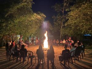 a group of people sitting around a fire at night at Tadom Hill Resorts in Kampong Labohan Dagang