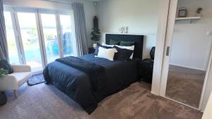 a bedroom with a bed with pillows and a mirror at Riverside Retreat with River views in Auckland