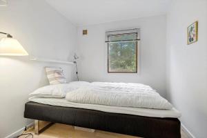 a bed in a white room with a window at 84230-Ebeltoft-Skovduevej-10 in Ebeltoft