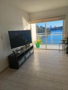 a living room with a large television and a large window at Vista Colonial, en el Residencial Riviera Colonial in Calero