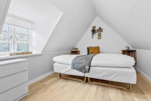 a white bedroom with a bed in a attic at 84109-Ebeltoft-Birkevej-1 in Øksenmølle