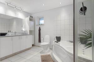a bathroom with a tub and a toilet and a sink at 84231-Ebeltoft-Magevej-50 in Ebeltoft +17 photos