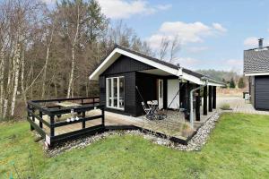 a black tiny house with a deck in a yard at 84231-Ebeltoft-Magevej-50 in Ebeltoft