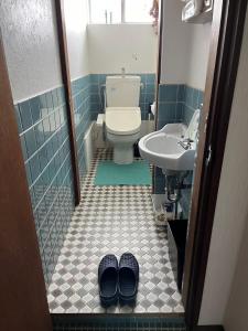 a bathroom with a toilet and a sink and a pair of slippers at Peace House Isonoura in Wakayama