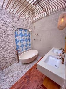 a bathroom with a white sink and a stone wall at Princessa Villa by Raminten in Pakem +19 photos