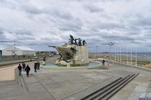 a group of people walking around a statue near the ocean at Morada Austral in Punta Arenas