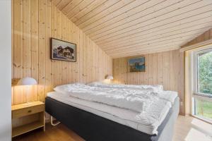 a large bed in a room with wooden walls at 84252-Ronde-Folfodvej-16 in Rønde