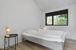 a white bedroom with a bed and a window at 8243-Knebel-Metholmvej-18 in Knebel