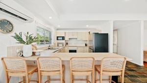 a kitchen with a large island with chairs around it at Gemburra By Holidayco in Pearl Beach