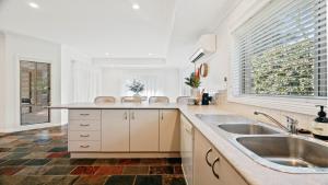 a kitchen with a sink and a large window at Gemburra By Holidayco in Pearl Beach