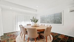 a dining room with a wooden table and chairs at Gemburra By Holidayco in Pearl Beach +12 photos