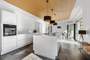 a kitchen with white cabinets and a wooden ceiling at 8244-Knebel-Metholmvej-20 in Knebel +19 photos