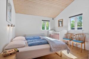 a bedroom with a bed and two chairs and windows at 30383-Odder-Lyngbakkevej-10 in Odder