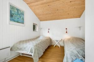 two beds in a room with white walls and wooden ceilings at 30512-Odder-Hasselvaenget-9 in Odder
