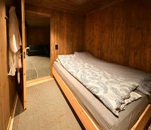 a small bed in a wooden room with a doorway at Architect-Designed Log Cabin By Myllavannet in Lunner