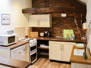 a kitchen with white appliances and a brick wall at Rebecca Puddle Duck Cottage in Bassenthwaite +21 photos