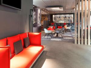 a restaurant with a red couch and tables and chairs at ibis Gent Centrum Opera in Ghent