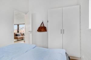 a white bedroom with a bed and a closet at 40149-Juelsminde-Gl-Dykjaer-14 in Juelsminde