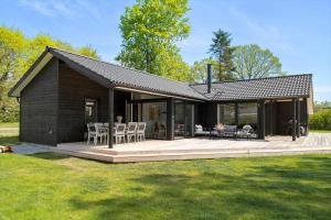 a small black house with a deck and chairs at 30319-Odder-Grindevej-19 in Odder