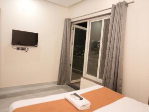 a bedroom with a bed and a tv and a window at Life Tree Hotel and Banquet Hall, Sector 63A in Noida