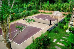 a tennis court in a garden with a tennis racket at Campo De Sole Villa Hoa Binh in Hòa Bình