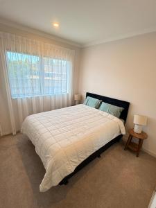 a bedroom with a large bed and a window at Modern Private 2BR Unit in Takapuna in Auckland