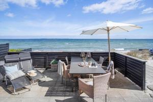 a table and chairs with an umbrella on the beach at 30594-Odder-Toldvejen-45-H in Odder +27 photos