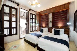 two beds in a room with windows at Cheva Gallery Boutique Hotel in Chiang Mai