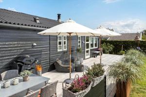 a patio with an umbrella and a table and chairs at 40159-Juelsminde-Mirabellevej-1 in Juelsminde