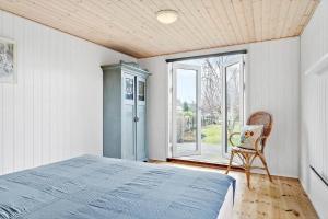 a bedroom with a bed and a chair and a window at 30461-Odder-Hulager-6 in Odder