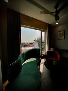 a living room with a green couch and a window at Hotel Mango Groves in Kotdwāra