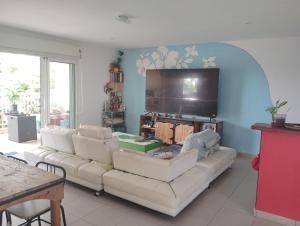 a living room with a couch and a flat screen tv at La chambre Ganesh in Saint-André