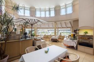 ein Restaurant mit weißen Tischen und Stühlen und Fenstern in der Unterkunft Awashima Hotel in Numazu