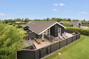 a black house with a deck and chairs on it at 40501-Juelsminde-Pot-Strandby-251 in Sønderby